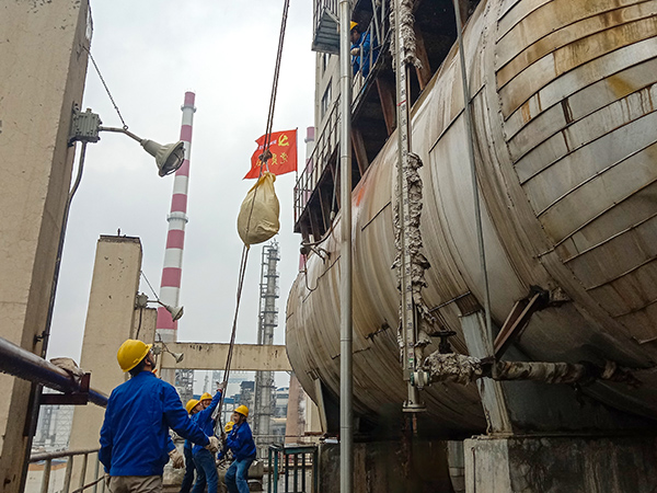 5月10日中午，在動力車間三期工藝除氧器地面，黨員突擊隊隊員用滑輪往工藝除氧器平臺運送鋼絲網(wǎng)，用以纏繞新填料.jpg